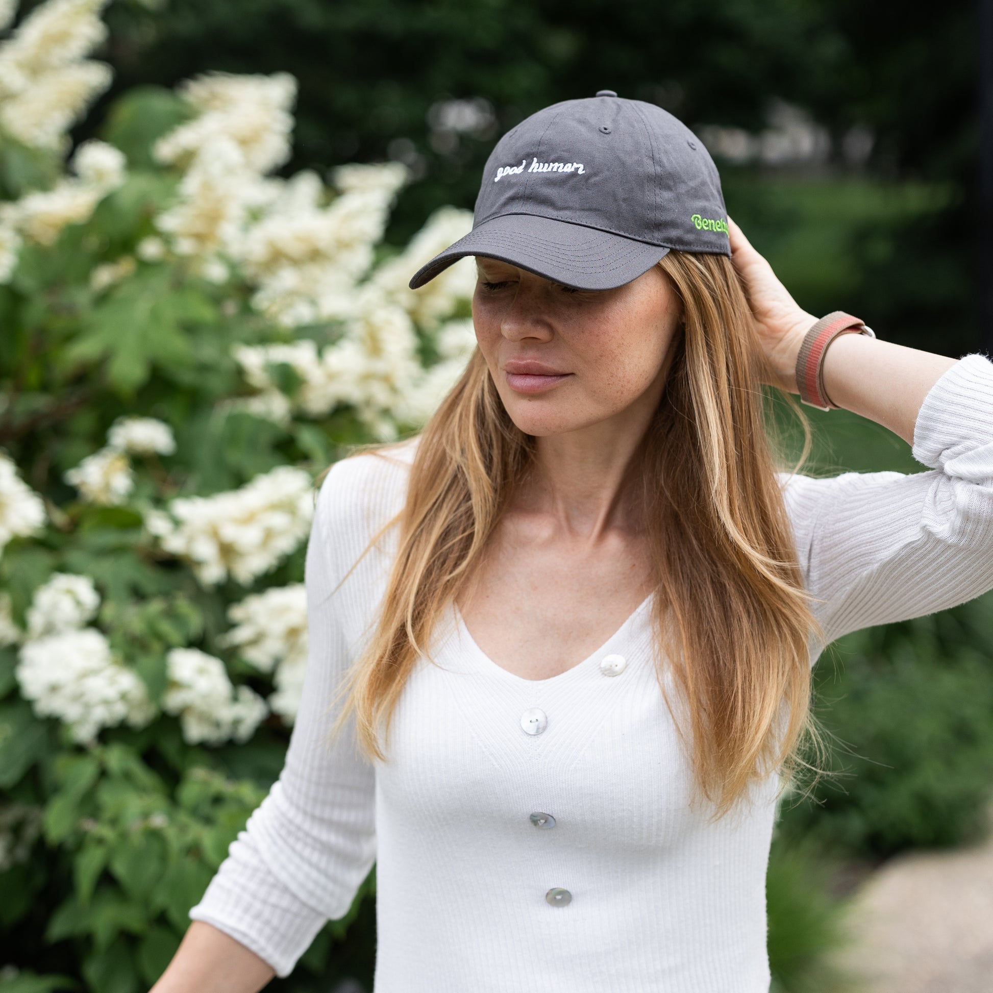 Female model wearing grey embroidered hat that says "Good Human."