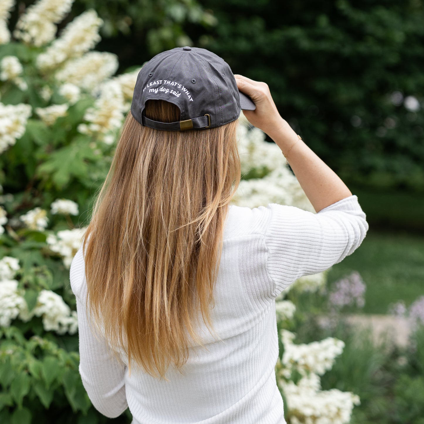 Female model wearing grey embroidered hat that says "Good Human, at least that's what my dog said."
