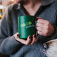 person holding Benebone branded green insulated mug wit hcover  with text printed on it "good human"